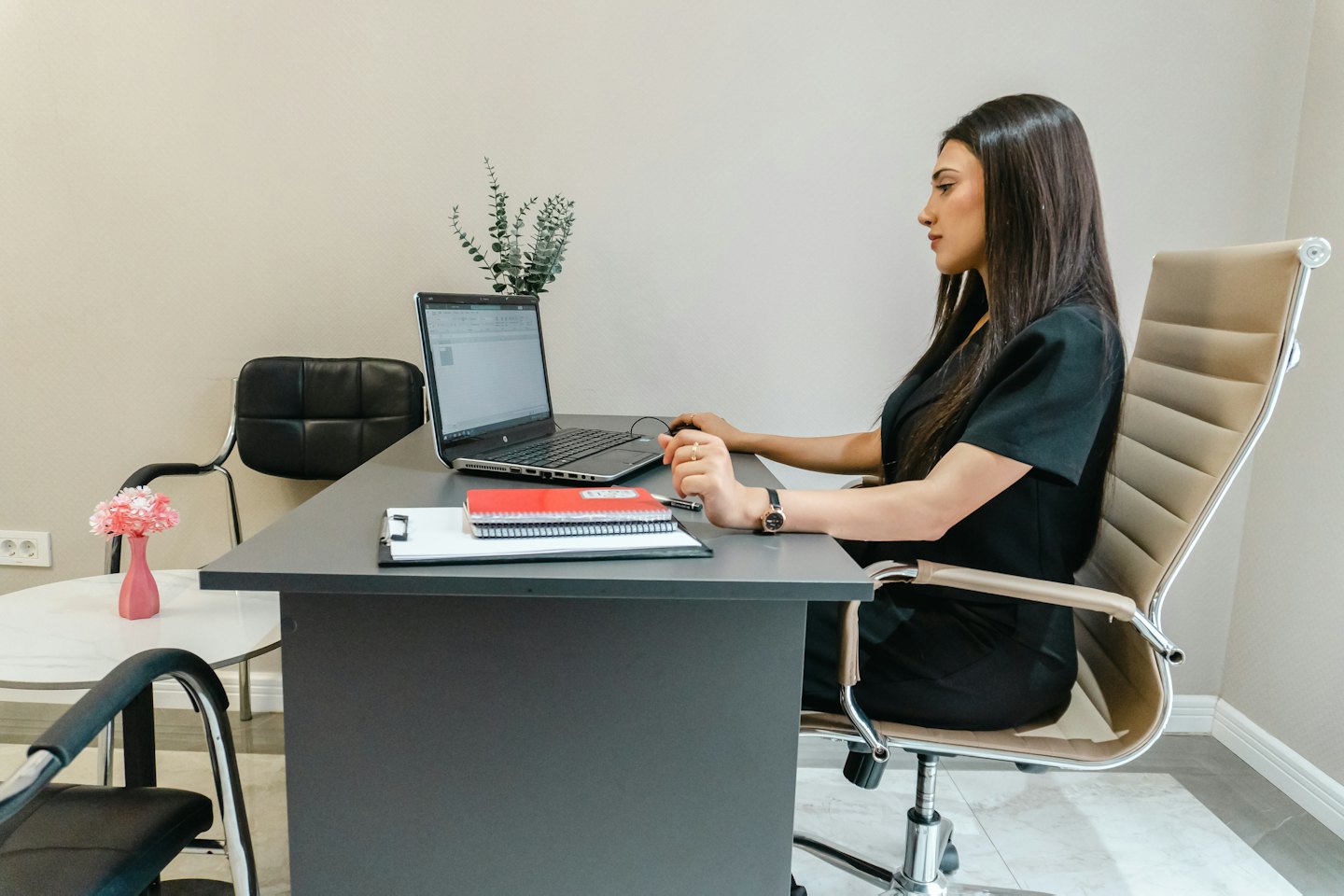 Woman working on a laptop at a modern office desk.